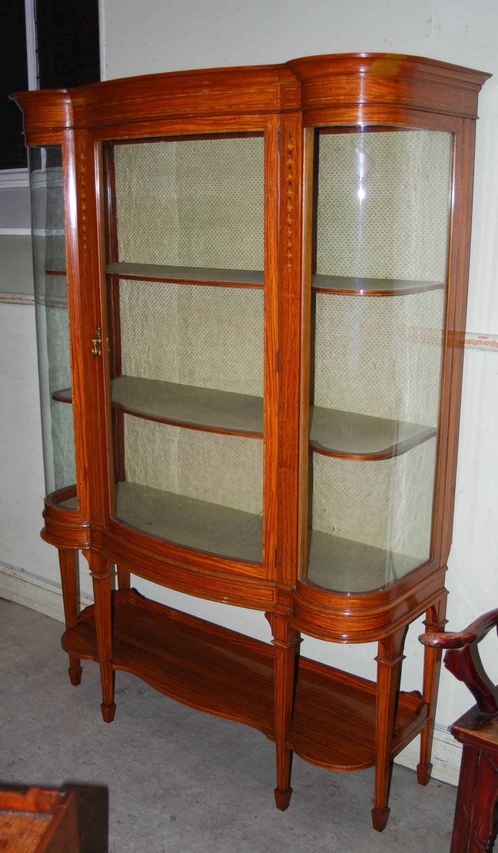 An Edwardian satinwood, ebony and boxwood lined display cabinet, the shaped cornice above a single