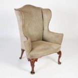 An early 20th century mahogany wing armchair, the grey upholstered back, arms and seat with brass