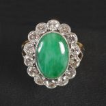 A mid 20th century yellow and white metal jade and diamond cluster ring, centred with an oval jade