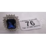 Large silver square ring set with large dark blue stone surrounded by white cut stones