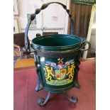 Wrought iron stand holding green bucket emblazoned with a coat of arms