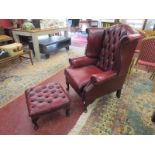 Red leather buttoned wing-back armchair with matching footstool