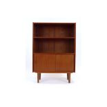 A 1970's Danish teak bookcase, the open front over two sliding doors on turned legs,