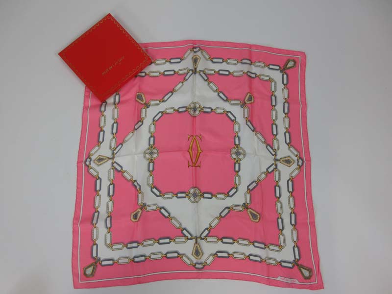 A Must De Cartier silk scarf decorated with a chain link pattern on a pink ground.