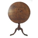 A mid 18th century oak tripod table, the circular tilt top on a turned column and three splay legs,