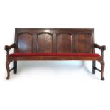 A mid 18th century oak settle, the back with four field panels over the seat with later cushion,