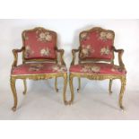 A pair of 19th century French giltwood open arm chairs,