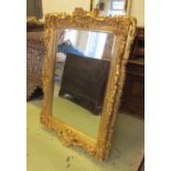 WALL MIRROR, gilt with scroll, leaf and flowerhead decoration and a rectangular bevelled plate,