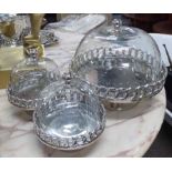 CAKE STAND, a pair, plus one larger in plated metal with glass domes, largest 36cm diam.