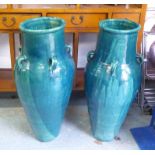 PERSIAN WINE VESSELS, a pair, in a turquoise glaze, 92cm H.