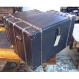 TRUNKS, a graduated pair, brass and black leather bound, largest 46cm H x 71cm x 40cm.