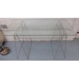 DESK, a glass top on a pair of polished metal supports with undertier, 70cm D x 136cm W.