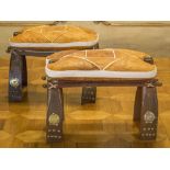 BEDOUIN STOOLS, a pair, with Egyptian motif embossed leather seats, 40cm H x 56cm W x 30cm D.