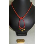 VICTORIAN GILT CORAL MOUNTED PILLBOX, three gold charms and silk and small red coral bead.