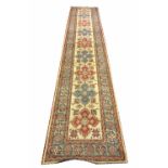 KAZAK RUNNER, 445cm x 85cm, of multiple medallions on ivory field.