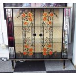 GLAZED CABINET, 1960's, floral painted glass doors, mirrored surround on turned supports,