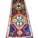 TURKISH KARAPINAR RUNNER, 450cm x 120cm, of three ivory and polychrome medallions on ruby field.