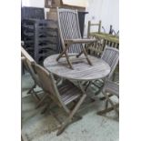 GARDEN TABLE, circular weathered teak, 119cm diam x 73cm H and six folding chairs 50cm W x 94cm H.