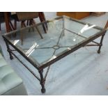 LOW TABLE, Giacometti style, the glass top on a wrought metal base with brass snake detail,