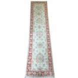 FERREGHAN RUNNER, 246cm x 60cm, of palmettes on ivory, within corresponding ruby borders.