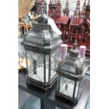 STORM LANTERNS, a graduated pair, of square form within a metal frame, 68cm and 48cm H.