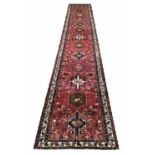 HERIZ RUNNER, 495cm x 83cm, rows of geometric medallions on a ruby field,