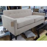 SOFA, two seater, buttoned back with square arms in a natural upholstery on splayed ebonised legs,