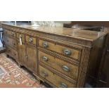 DRESSER BASE, George IV oak and mahogany crossbanded containing eight drawers and two doors,
