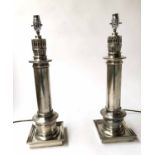 LAMPS, a pair, silvered metal, each with column plinth and square base, with shades approx 70cm H.