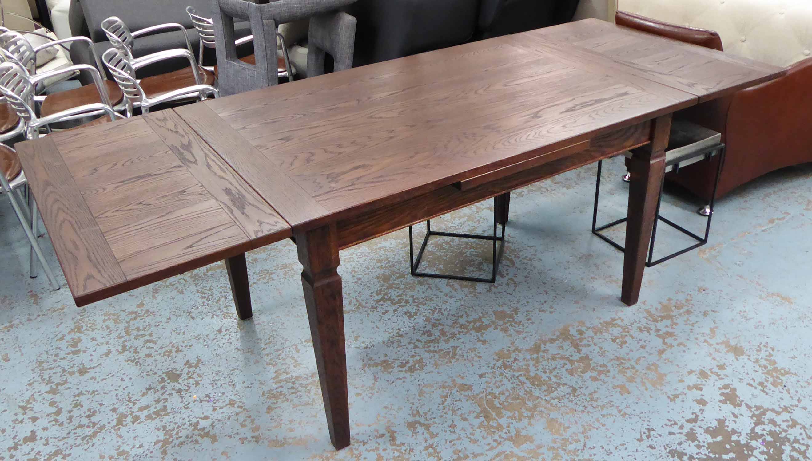 DINING TABLE, extending (two leaves) in stained oak on square supports,