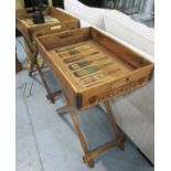 DRINKS TRAYS ON STANDS, a pair, stamped with various champagne houses, 76cm H.