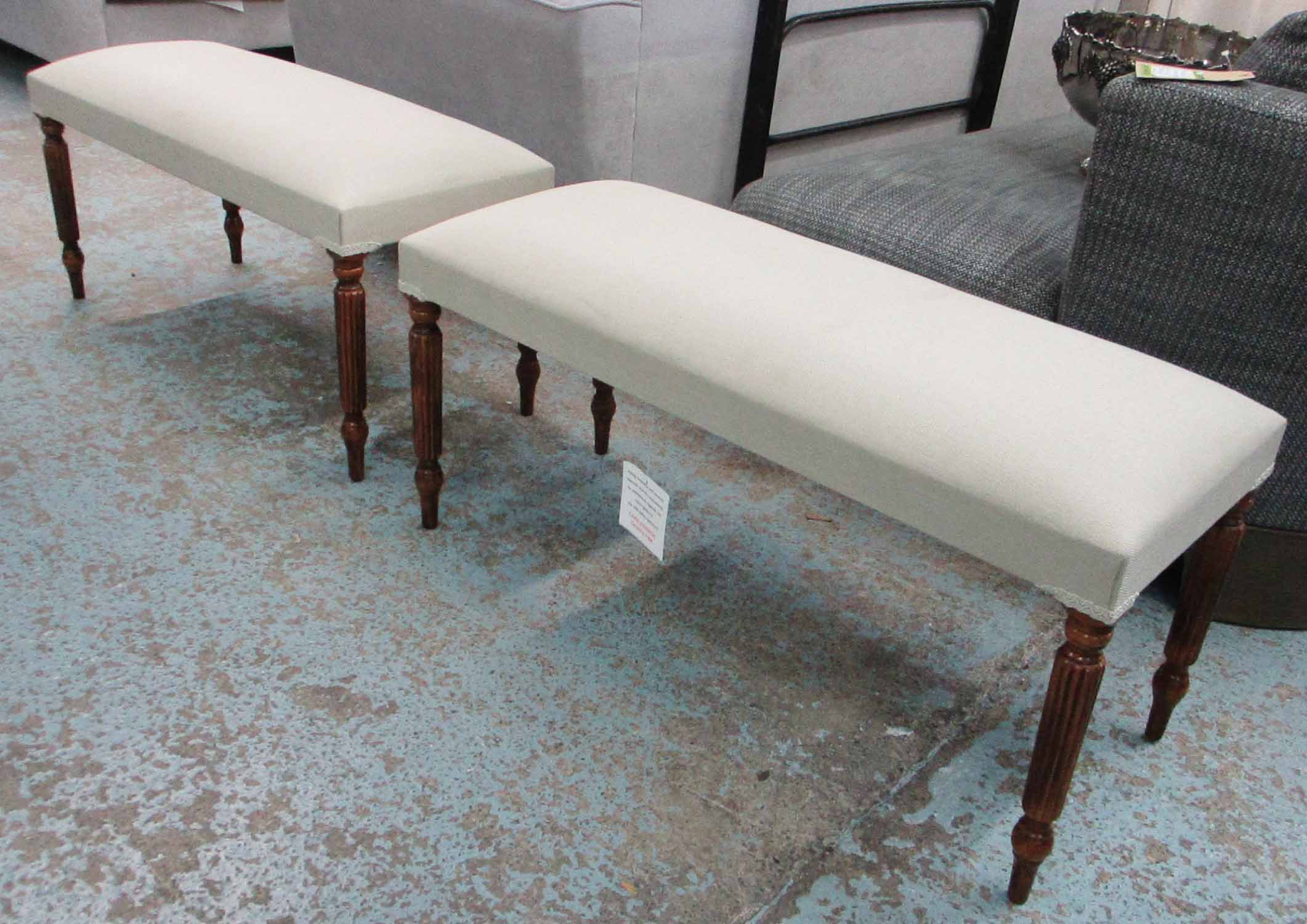 STOOLS, a pair, each with beige upholstery on reeded turned supports, 98cm L x 46cm H x 40cm D.