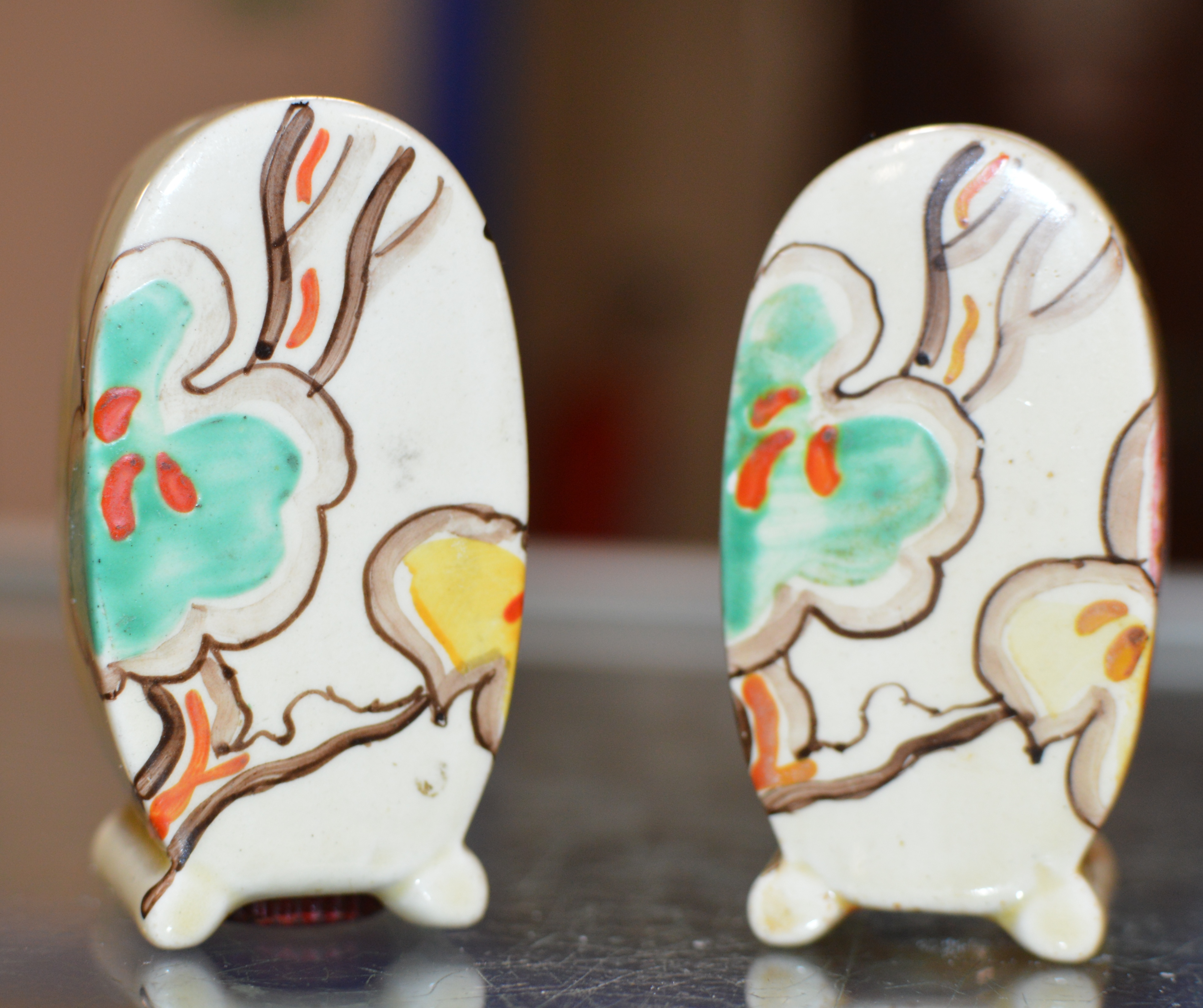 A PAIR OF ART DECO HAND PAINTED SALT & PEPPER CRUETS IN THE STYLE OF CLARICE CLIFF