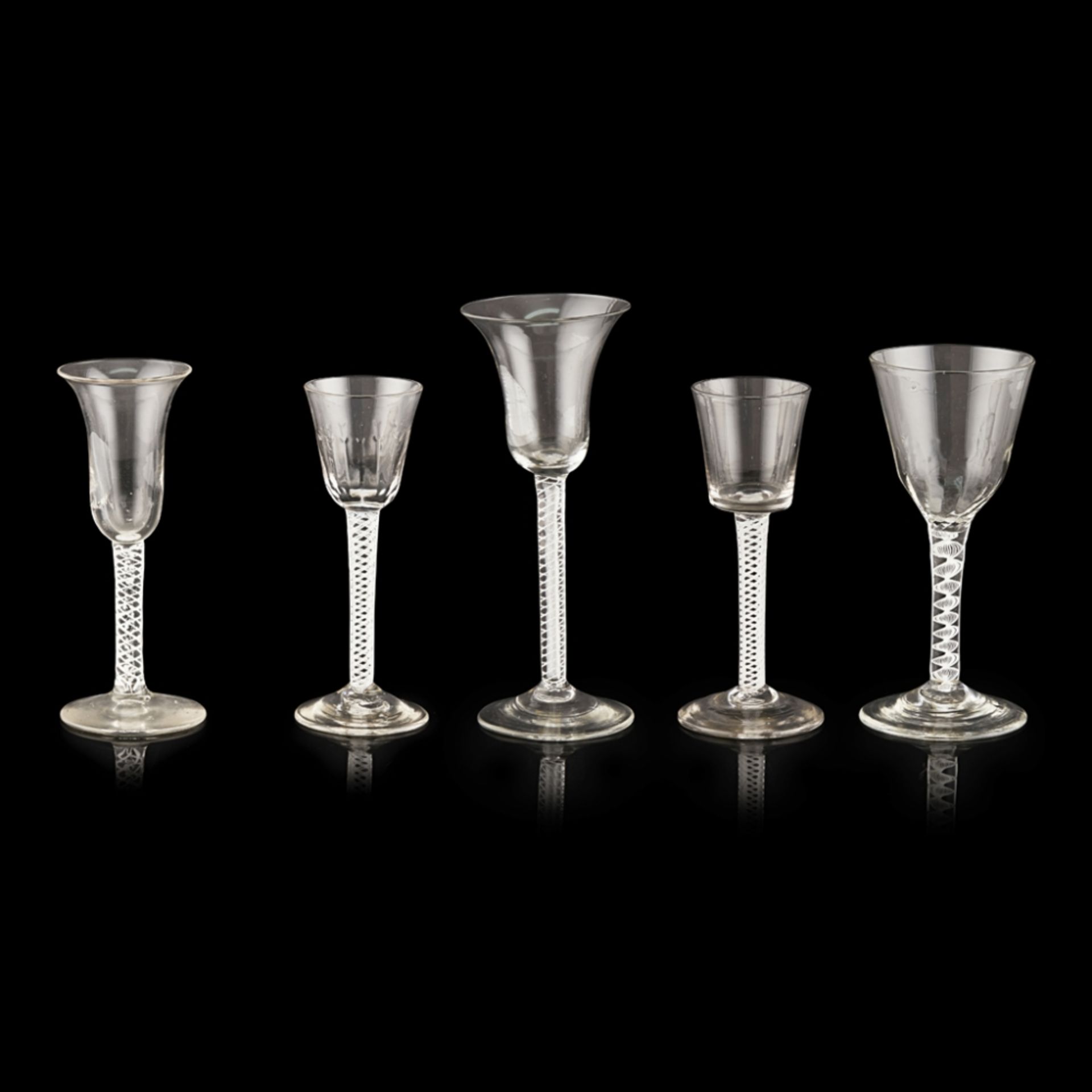 FOUR GEORGIAN TWIST STEM WINE GLASSESMID-18TH CENTURY comprising a bell bowled glass with a mixed