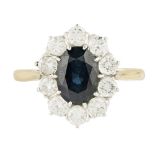 A sapphire and diamond set cluster ring claw set with an oval cut sapphire, in a border of ten round
