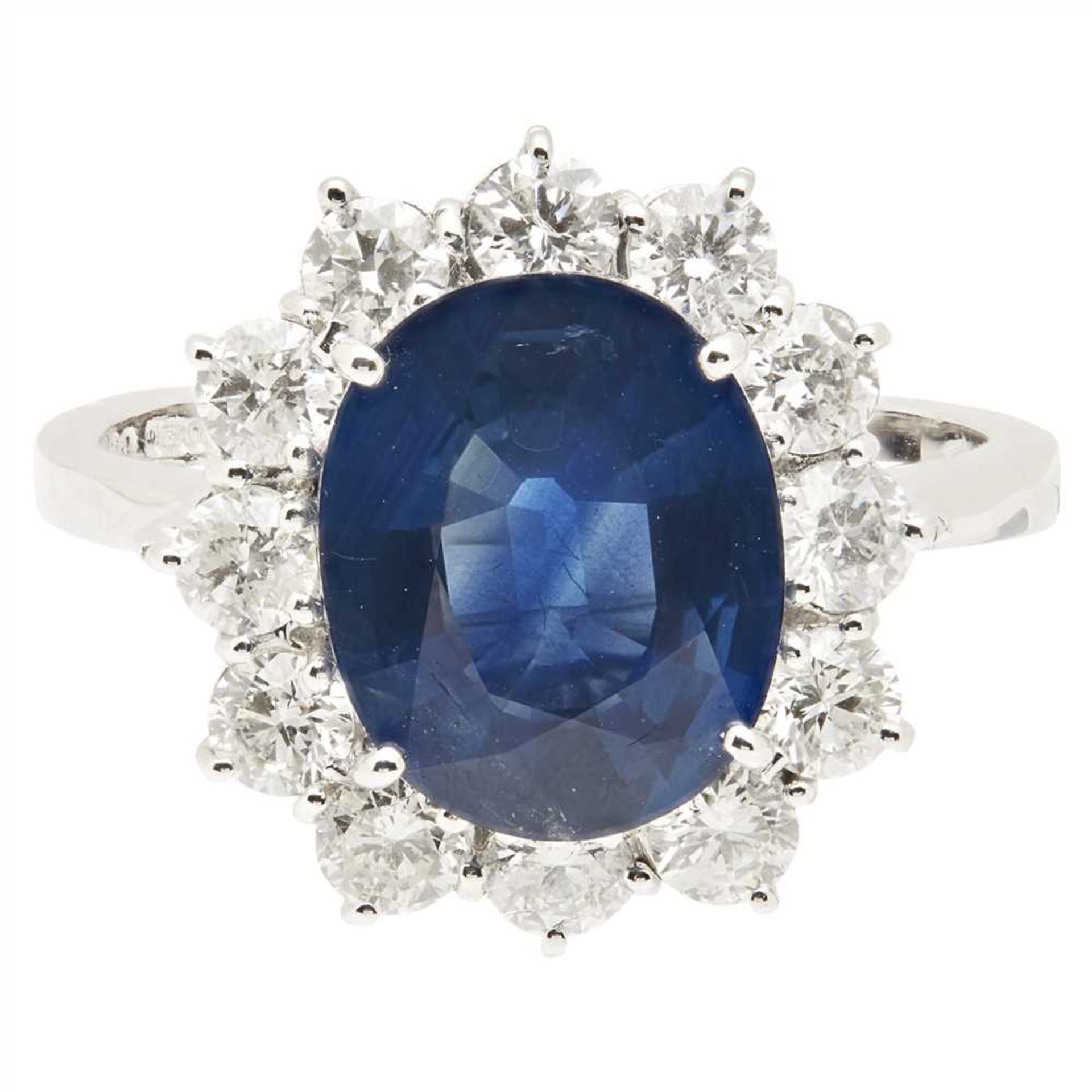 A sapphire and diamond cluster ring claw set with an oval cut sapphire in a border of round