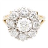 A diamond cluster ring claw set with a round brilliant cut diamond, in a border of smaller round