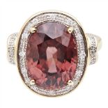 A pink tourmaline and diamond ring claw set with a oval cut pink tourmaline, the border, shoulders