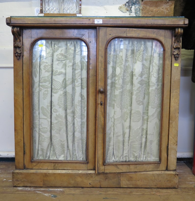 A mid Victorian walnut chiffonier, with twin glazed doors and carved corbels on a plinth base,