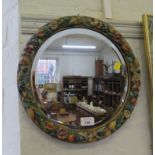 A polychrome framed wall mirror with flower and fruit decoration and bevelled plate 36cm diameter