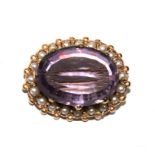 A 9 carat gold brooch, set with seed pearls and an amethyst colour stone