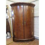 A George III mahogany bowfront corner cupboard, the later top over bowed doors on later bracket