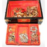An Oriental lacquer case, set with hardstones to the lid, containing a collection of costume