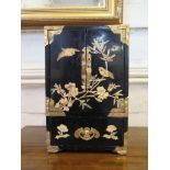 A Chinese lacquered cabinet with brass mounts, the pair of doors enclosing drawers, over a single