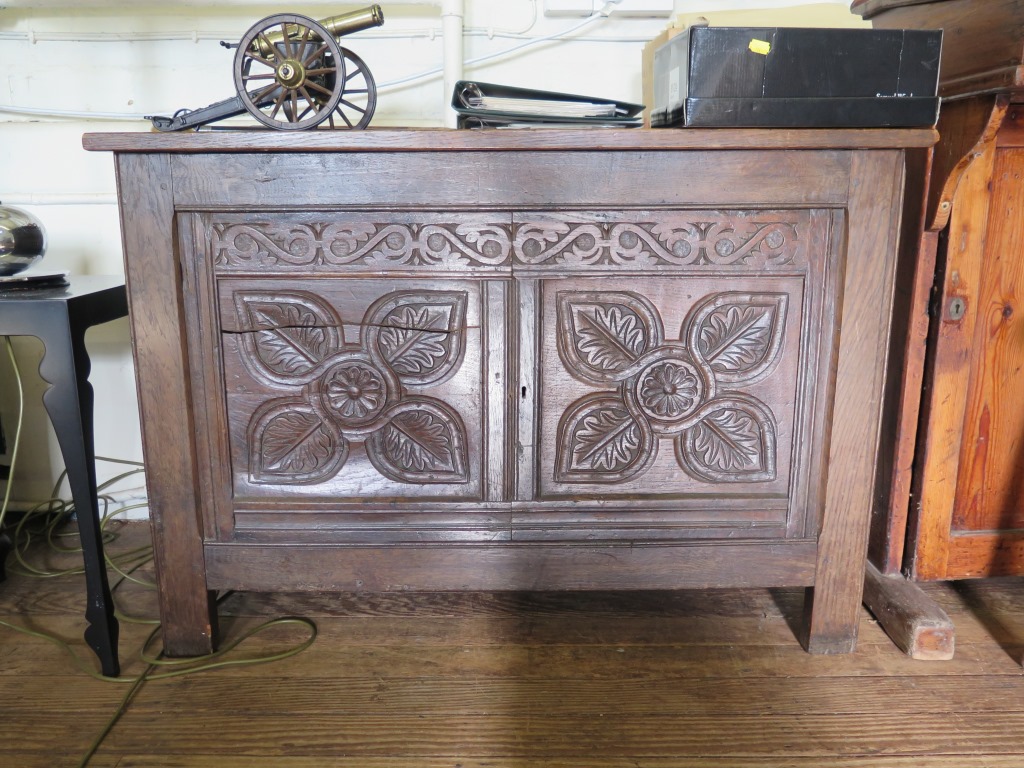 *A 17th century oak coffer, the triple panelled hinged lid over a foliate carved double panel