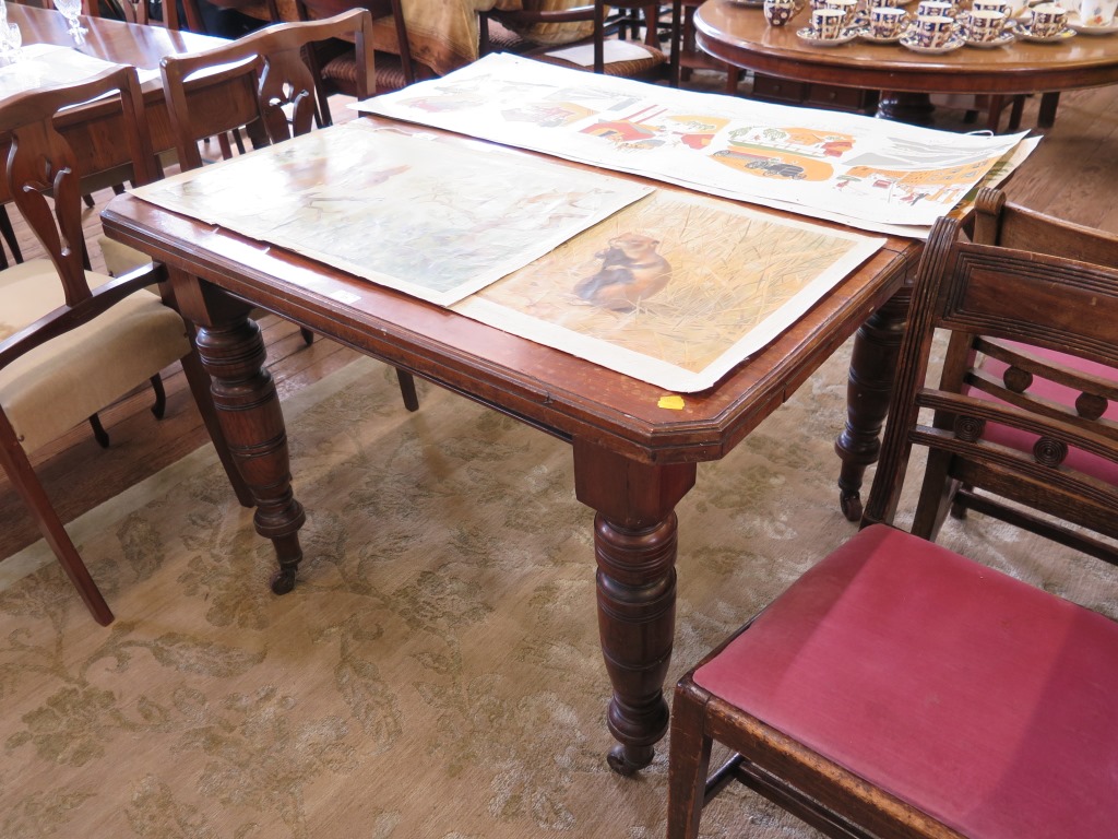 An Edwardian walnut windout dining table, with canted top on ring turned legs and castors, no