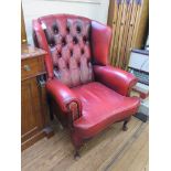 A red leather button back wing armchair