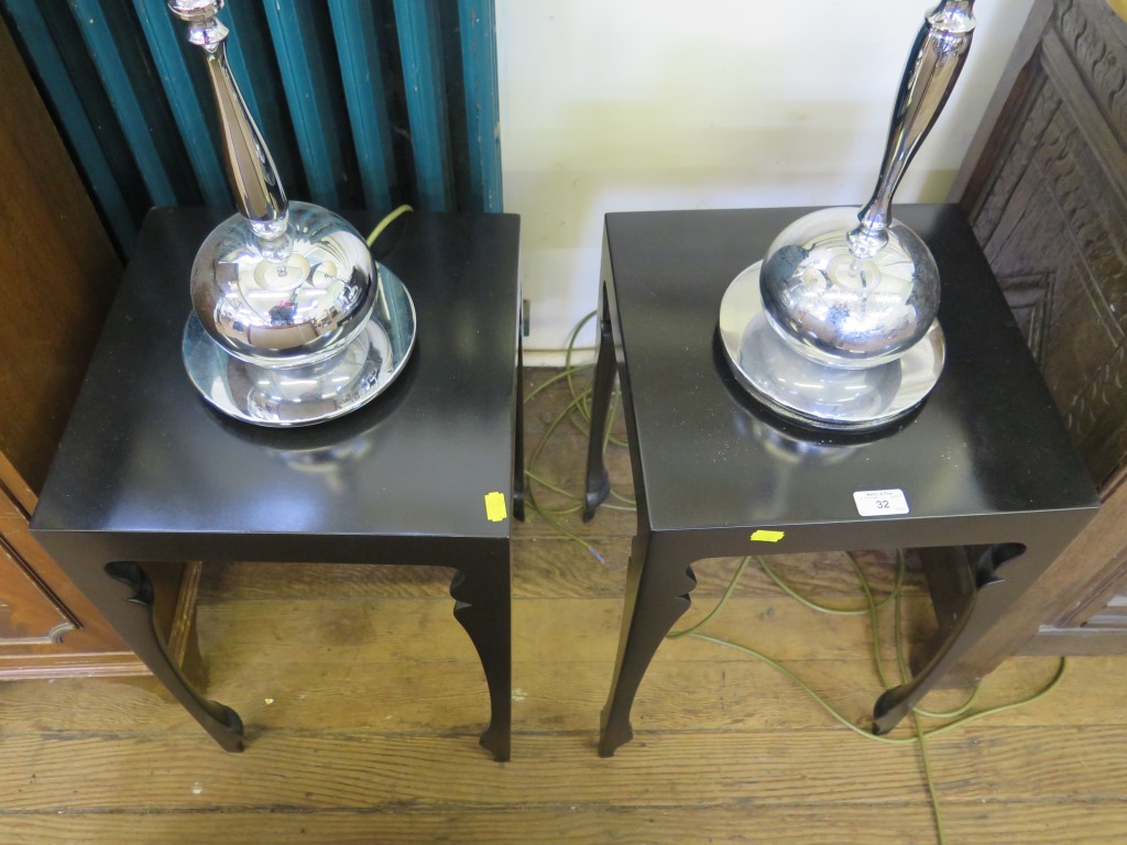 A pair of chromed table lamps fitted to ebonised tables 131cm high