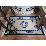 An oval rug in black and grey with rose decoration, 220cm x 161cm and a small Chinese rug (2)