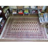 A Bokhara style rug, the three columns of thirteen red guls on a cream field within a multiple